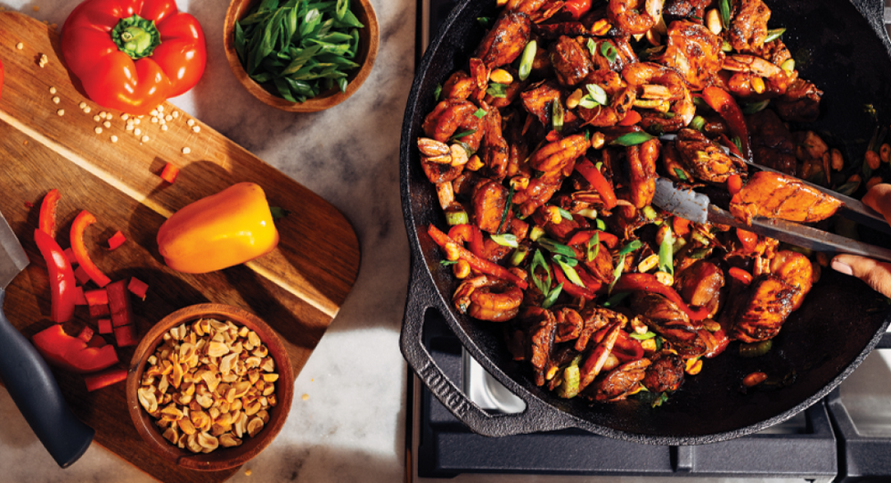 Someone cooking stir fry in cast iron wok