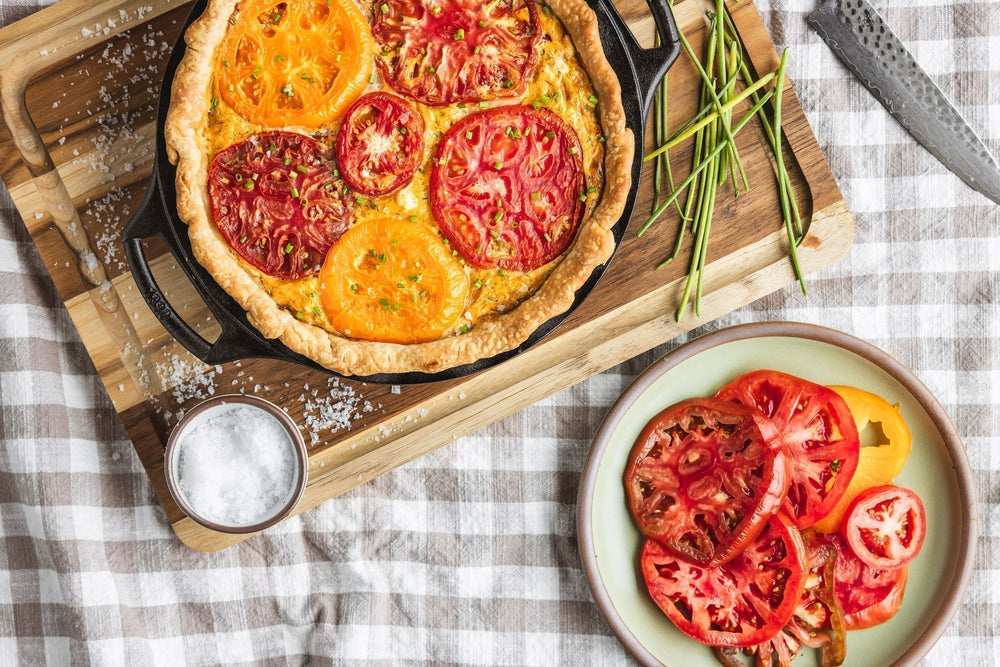 Tomato pie displayed in pan on top of cutting board.
