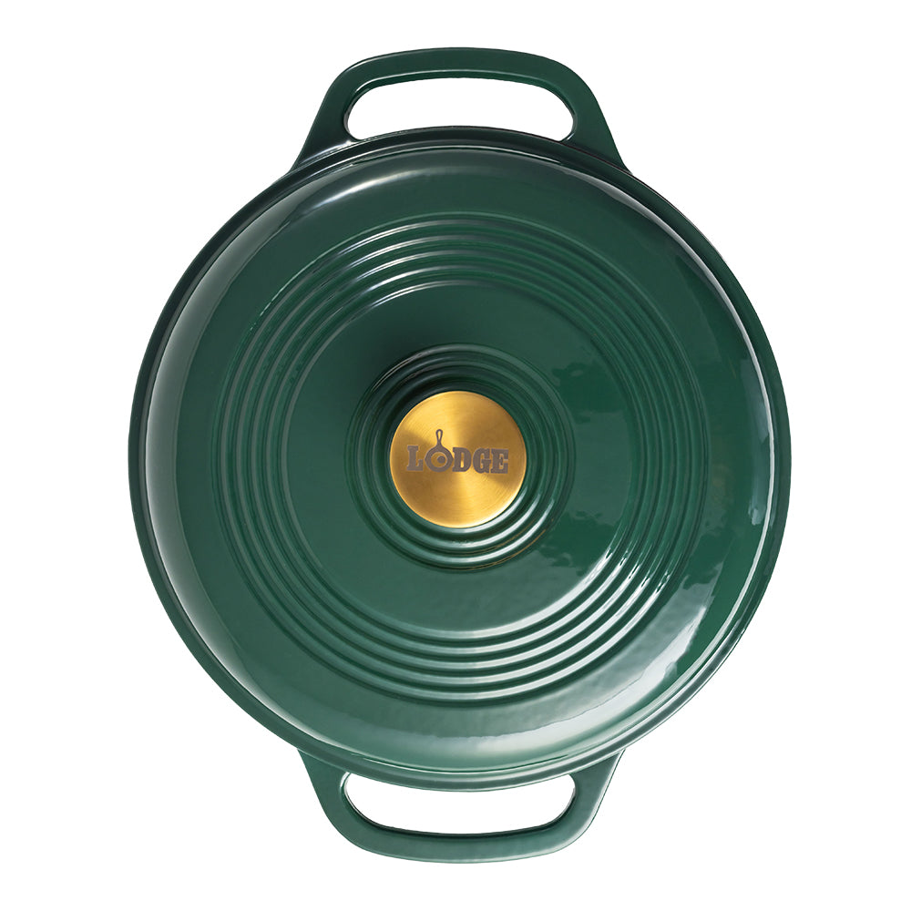 A green Lodge cast iron Dutch oven shown from a top-down view, featuring a circular lid with concentric ridges, two side handles, and a gold-colored center knob with the Lodge logo.