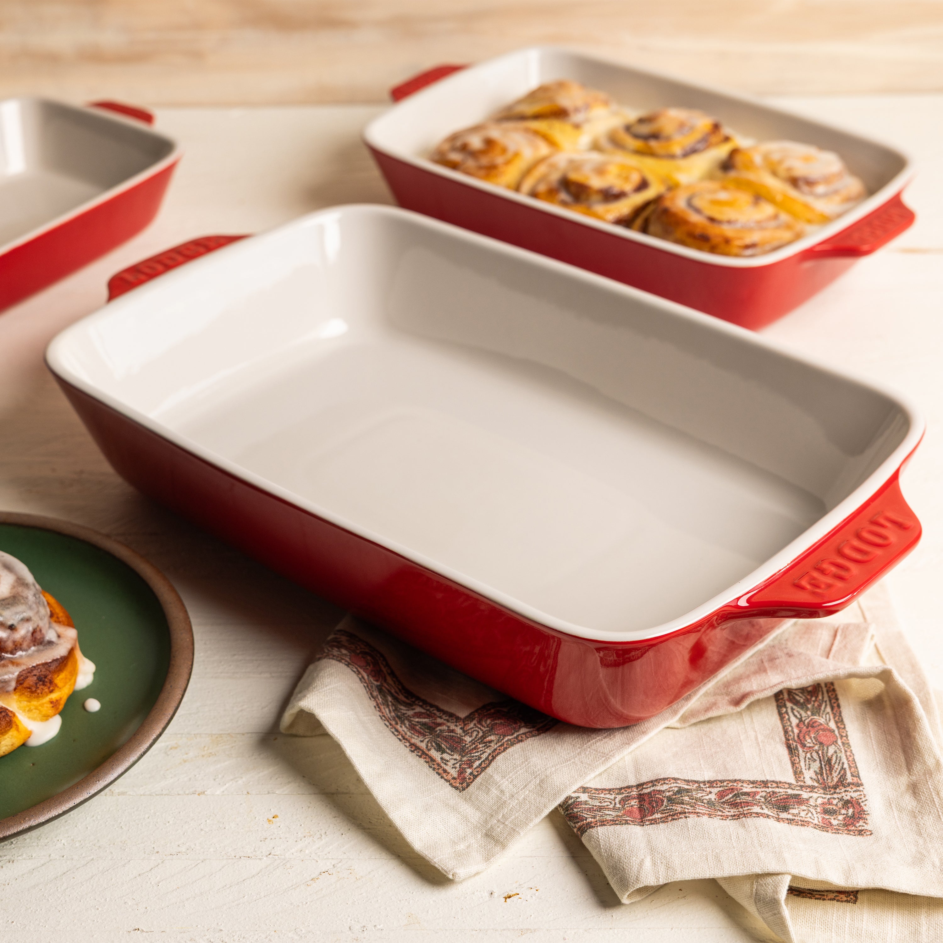 Cherry-red stoneware casserole dish with baked cinnamon rolls.