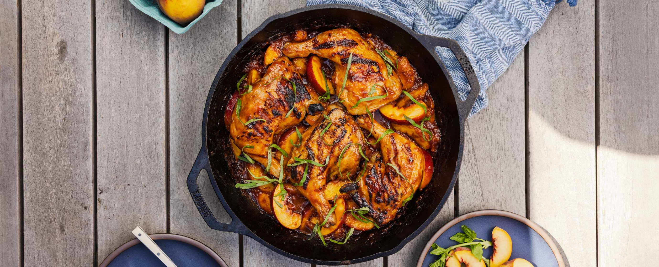 Skillet with roasted chicken and vegetables on a wooden surface