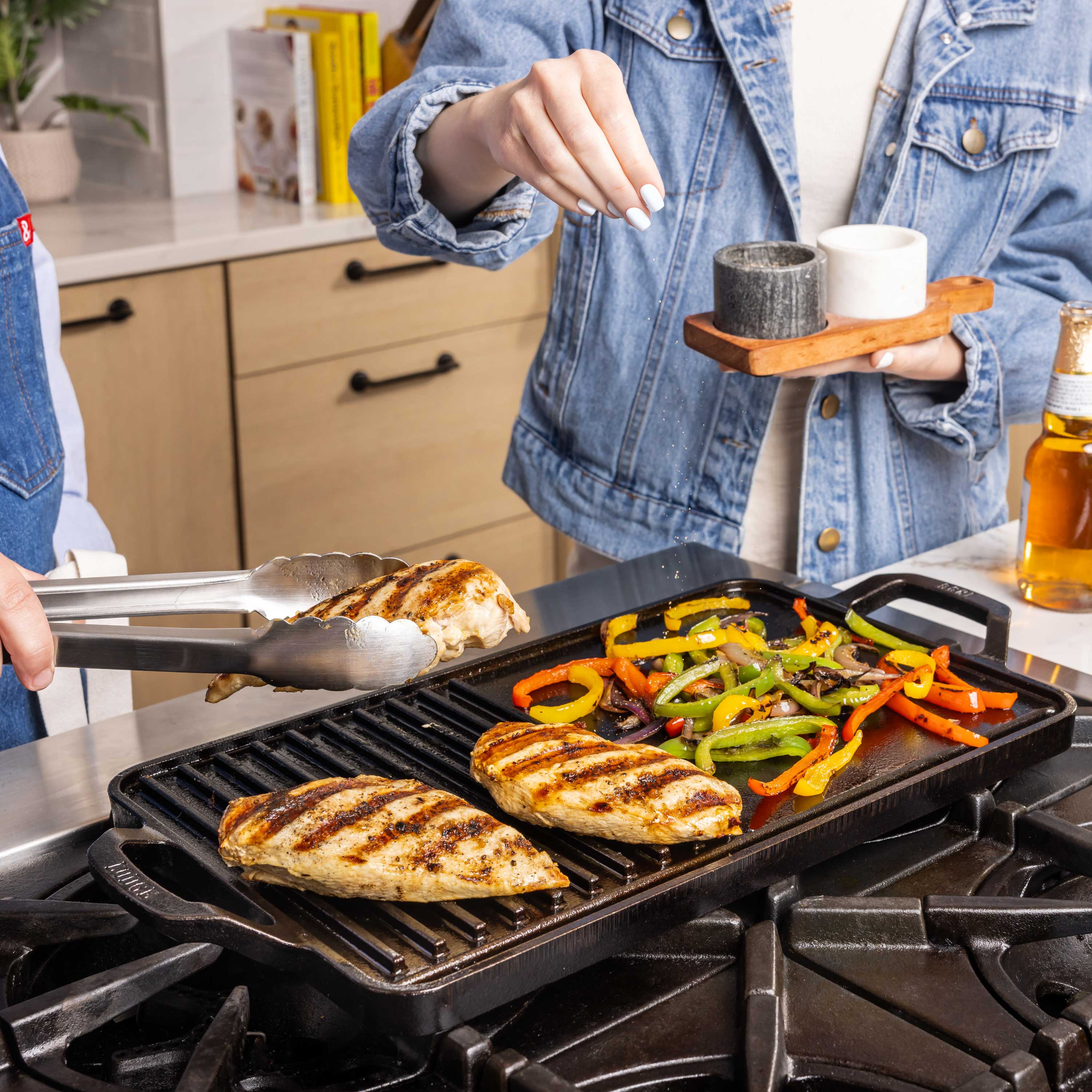 Person grilling chicken and vegetables on a griddle grill combo in a kitchen.