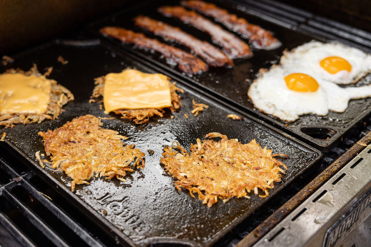 Grilled food items including hash browns, bacon, and eggs on a griddle.
