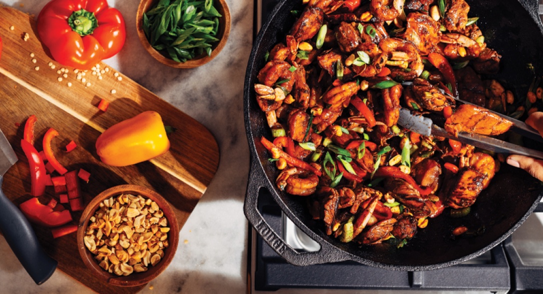 Someone cooking stir fry in cast iron wok