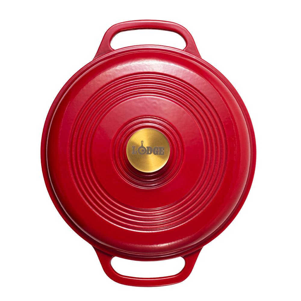 A red Lodge cast iron Dutch oven shown from a top-down view, featuring a circular lid with concentric ridges, two side handles, and a gold-colored center knob with the Lodge logo.