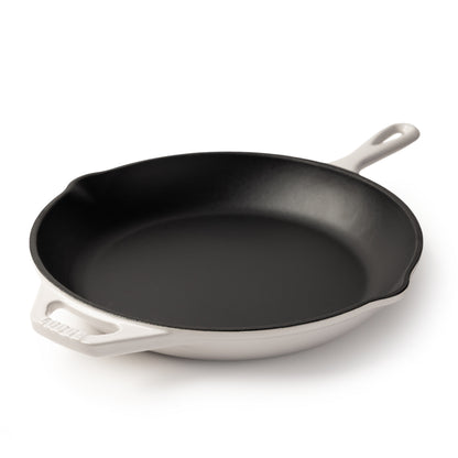 A cast iron skillet with a black interior and a white exterior, featuring a single loop handle on the right and a side handle on the left, photographed on a clean white background.