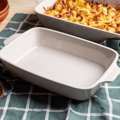 Oyster ceramic baking dish beside dish of fresh, baked pasta.