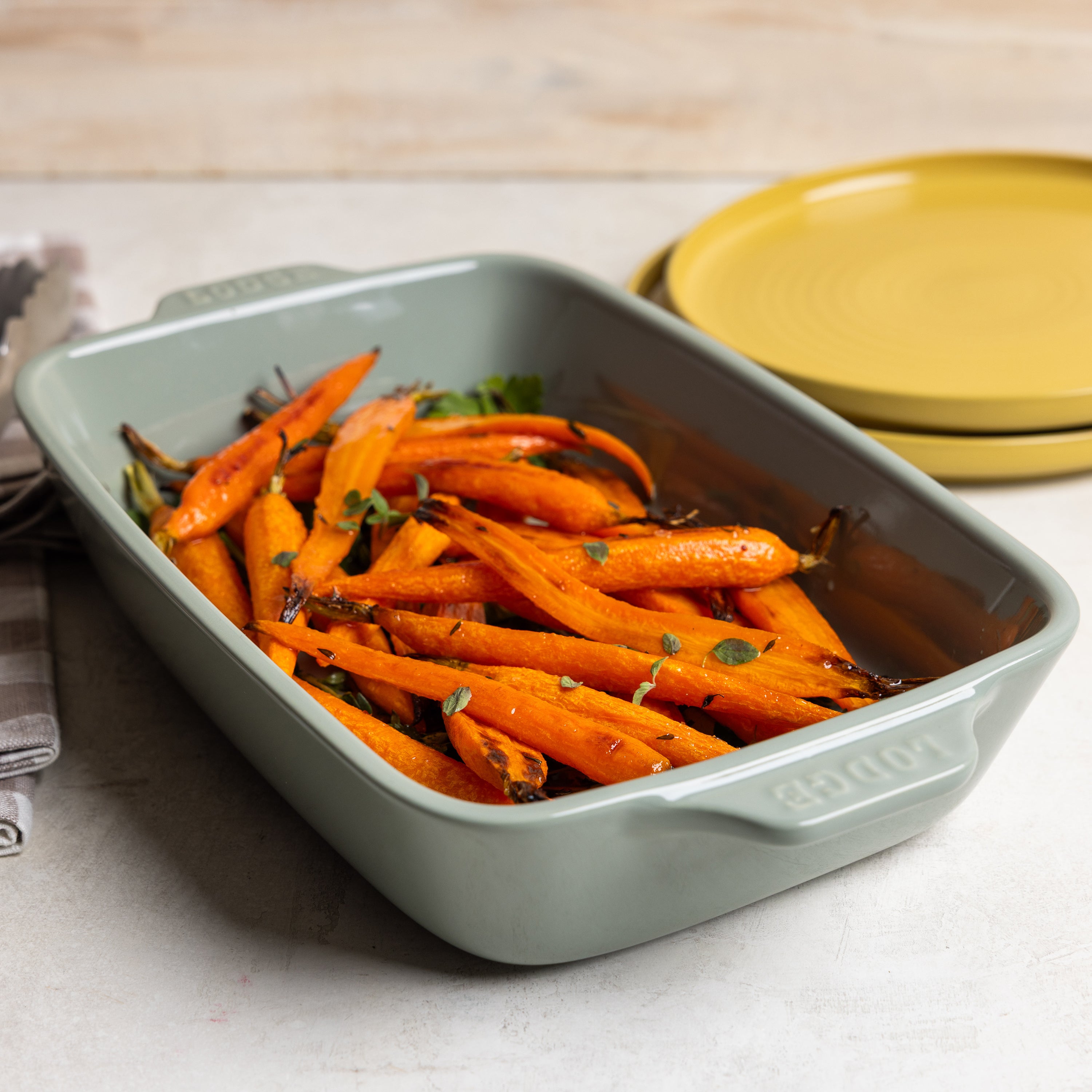 Roasted carrots in a green ceramic baking dish.