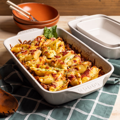 Baked pasta in white rectangular baking dish on checkered tablecloth.