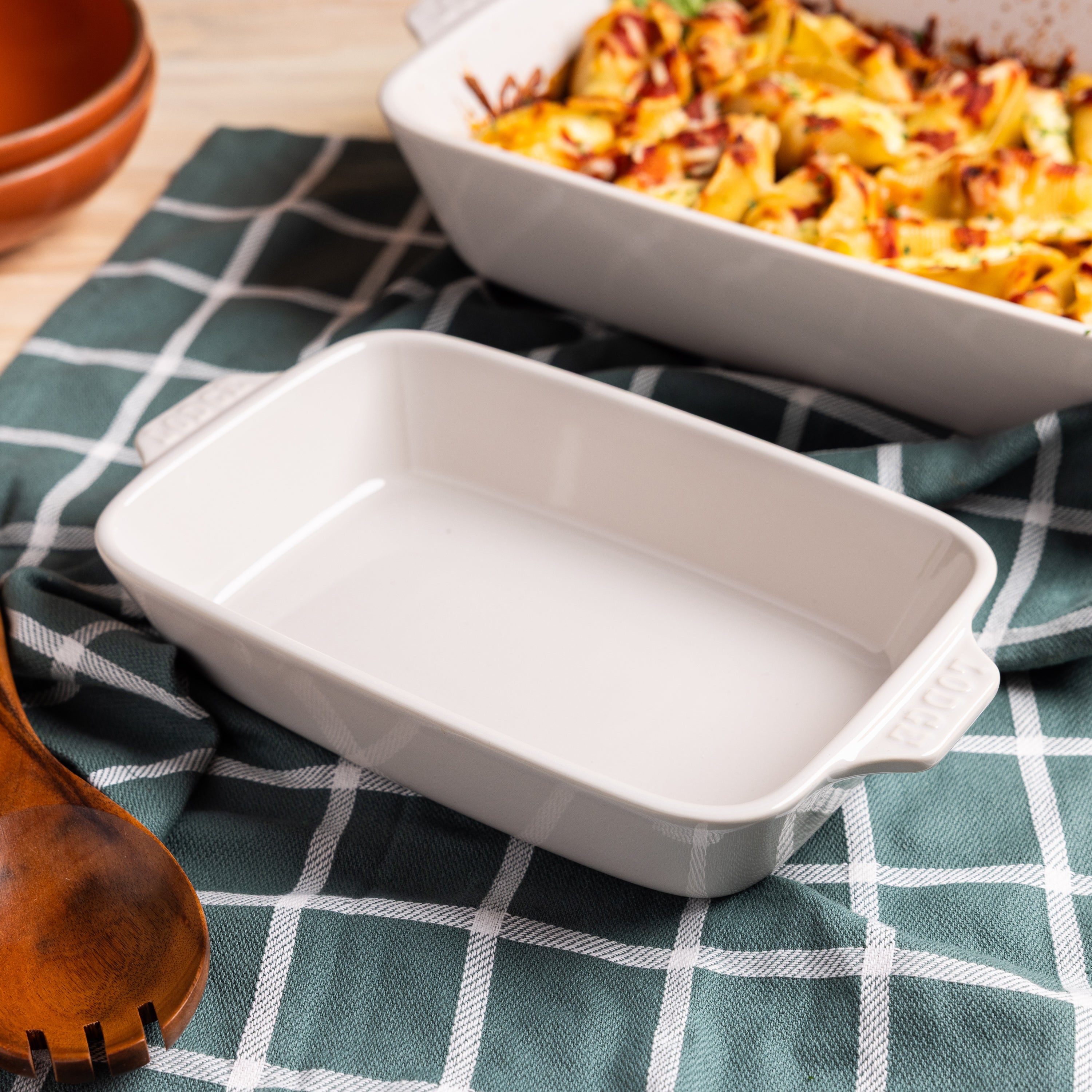 Oyster ceramic baking dish with a dish of pasta in the background.