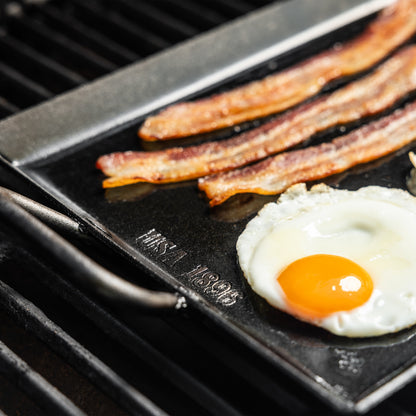 Close up of griddle handle while cooking eggs and bacon.