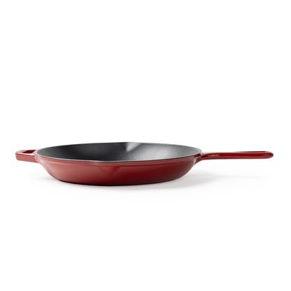 A red enameled cast iron skillet with a dark gray non-stick interior, shown from a side angle on a white background.