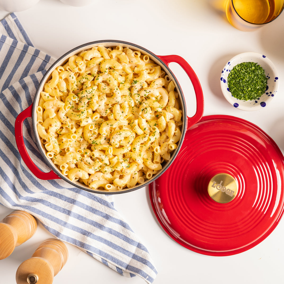 A top-down view of a creamy macaroni pasta in a red enameled cast-iron Dutch oven with a lid.