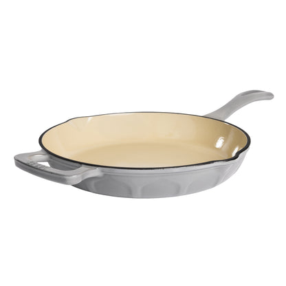 A gray enameled cast iron skillet with a cream-colored interior and a black rim, shown from a three-quarters angle on a white background.