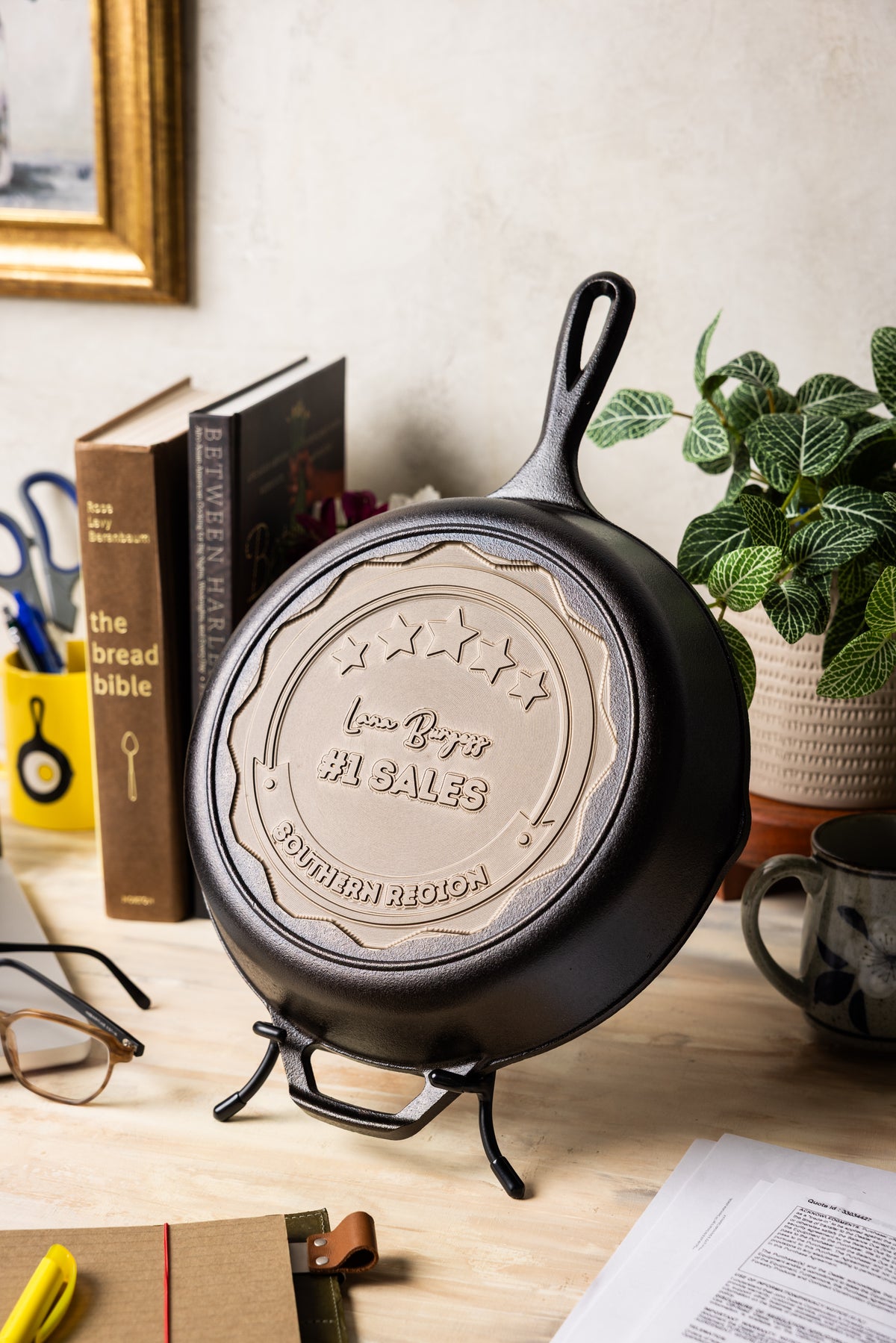 Cast iron skillet on a stand with a decorative emblem in a home setting