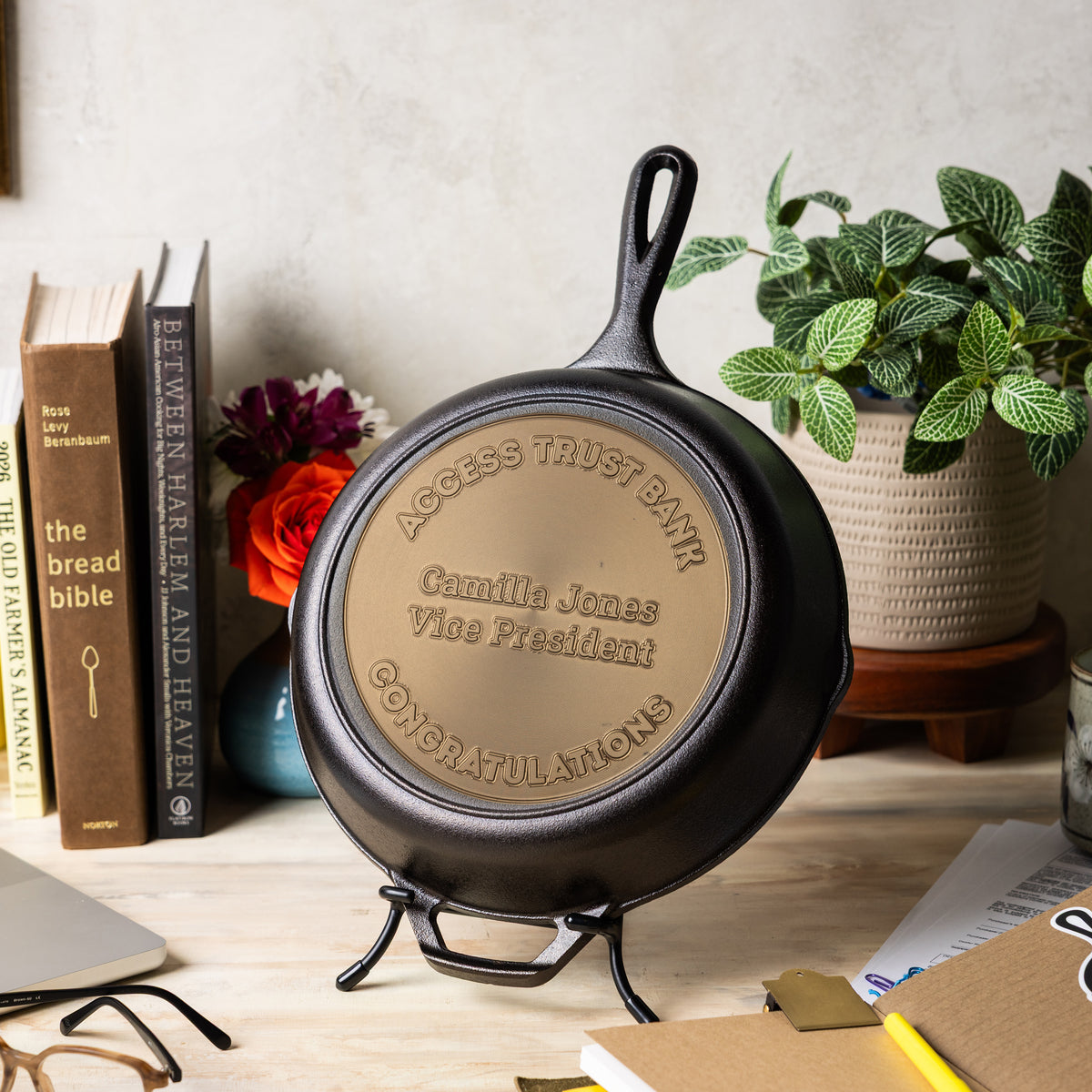 Personalized cast iron skillet on a stand with books and plants in the background