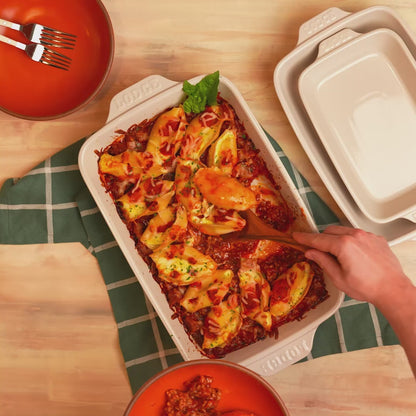 Baked pasta being served from stoneware casserole dish.