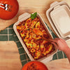 Baked pasta being served from stoneware casserole dish.
