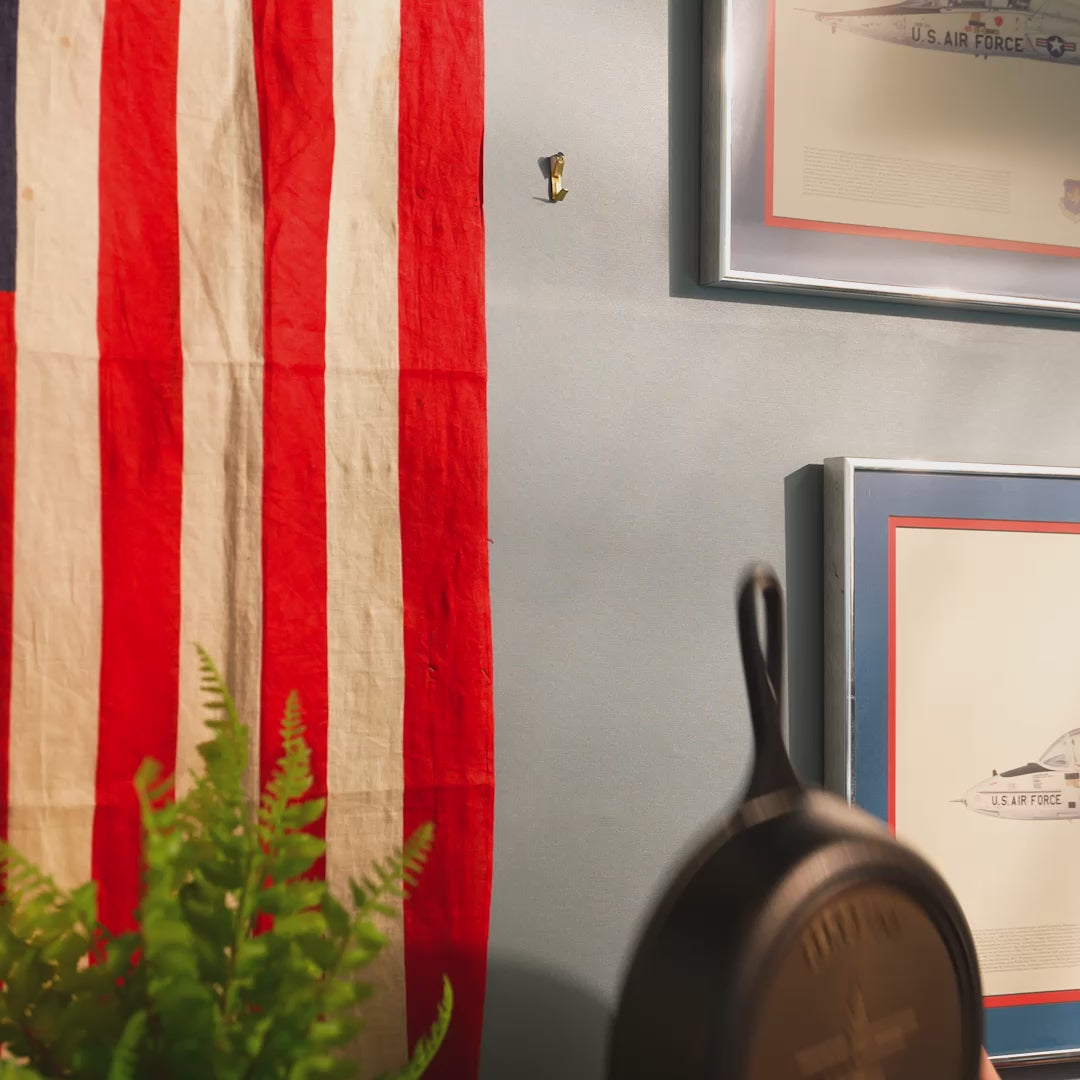 Personalized skillet being hung on wall near an American flag.