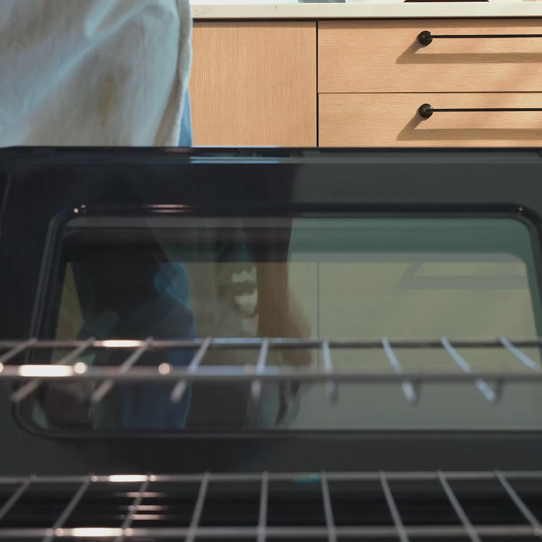 Someone placing dutch oven in the oven to prepare creamy Mac and Cheese.